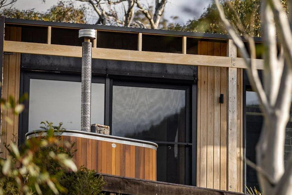 Wood-fired stainless steel hot tub with cedar cladding on modern New Zealand home balcony